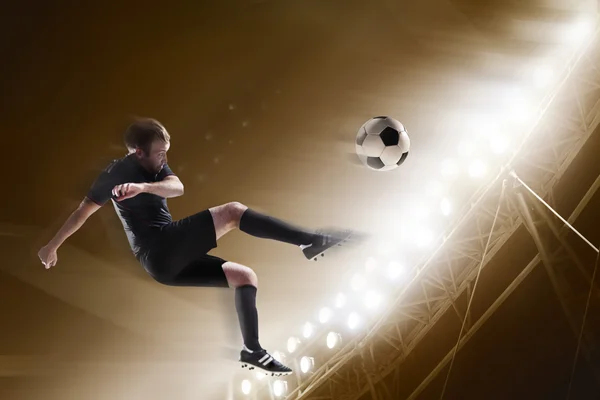 Спортсмен пинает футбольный мяч на стадионе — стоковое фото