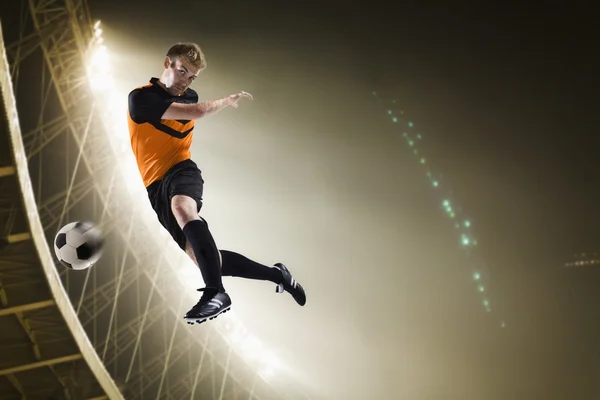 Спортсмен кидає футбольний м'яч на стадіоні — стокове фото