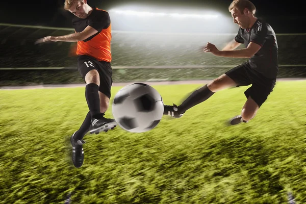 Två fotbollsspelare sparka en fotboll — Stockfoto