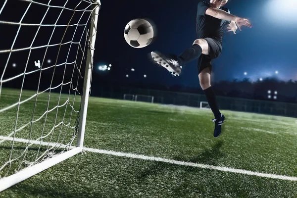 Atleta pateando pelota de fútbol en un gol — Foto de Stock