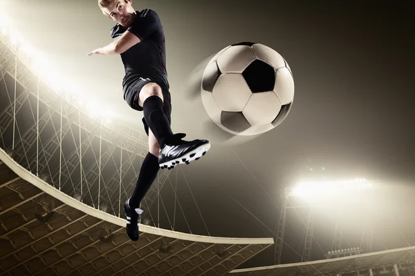 Athlete kicking soccer ball in stadium — Stock Photo, Image