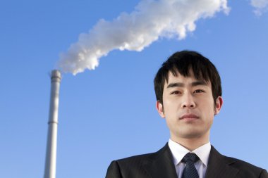 Businessman in Front of Smokestack clipart