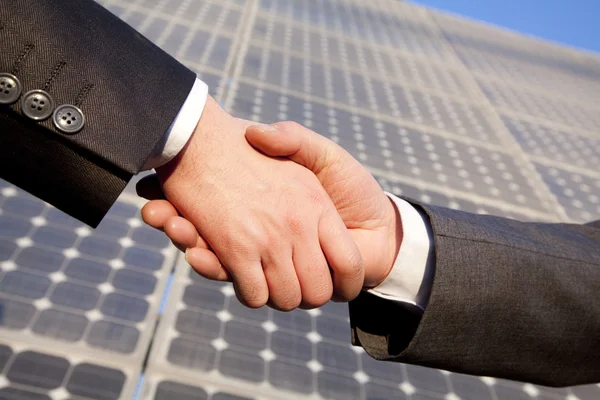 Apertando as mãos na frente de painéis solares — Fotografia de Stock