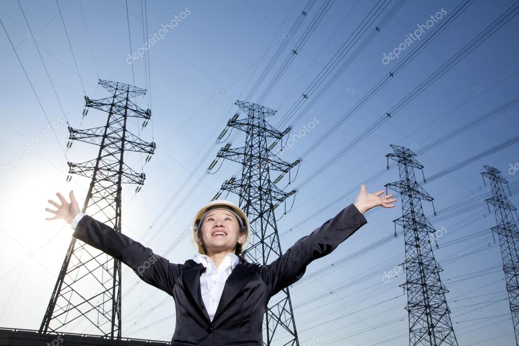 Businesswoman in front of power lines with arms oustretched