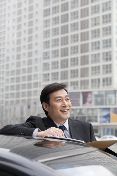 Hombre de negocios sonriendo, trabajando al aire libre en el coche — Foto de Stock
