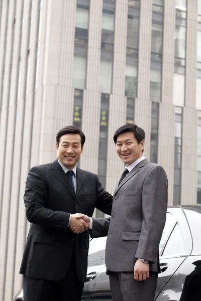 Двое бизнесменов пожимают руки на улице — стоковое фото