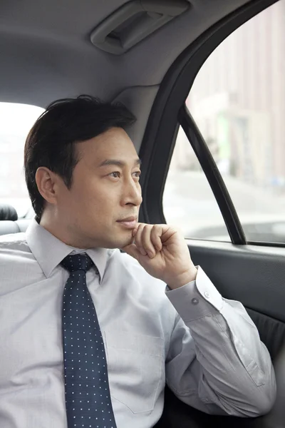 Businessman looking out car window — Stock Photo, Image