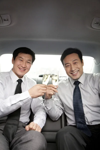 Бизнесмены тосты на заднем сиденье машины — стоковое фото