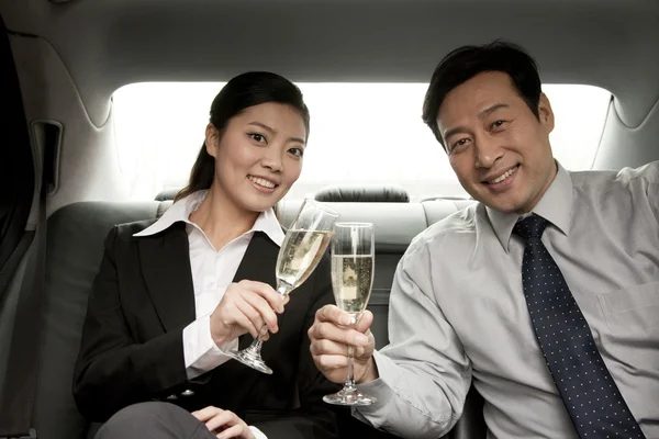 Business people toasting champagne back of car — Stock Photo, Image