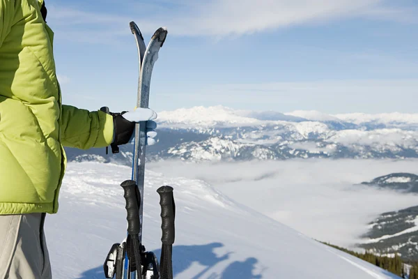 Мужчина лыжник, стоящий с лыжами на горе — стоковое фото