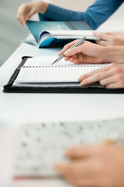 Mensen met boeken zitten aan tafel — Stockfoto