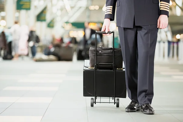 Pilot mit Koffern auf einem Flughafen — Stockfoto