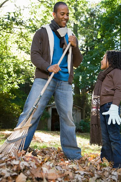 Father and daughter raking leaves — Stock Photo, Image