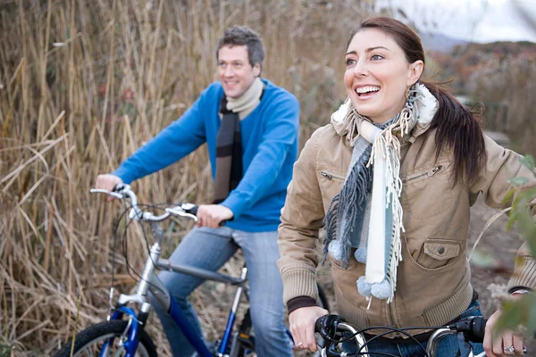 Couple riding on a bicycle in the field — Stock Photo, Image