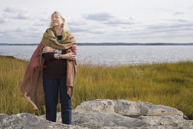 Bir göl kenarında duran üst düzey kadın