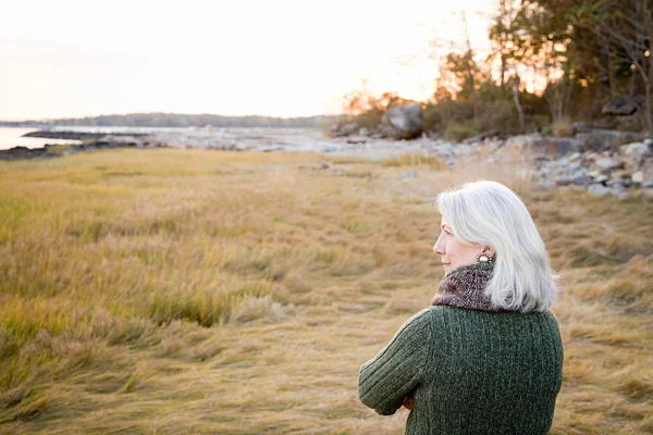 Žena stojící na trávě poblíž pobřeží — Stock fotografie