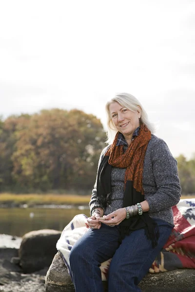 Äldre kvinna sitter på stenar — Stockfoto