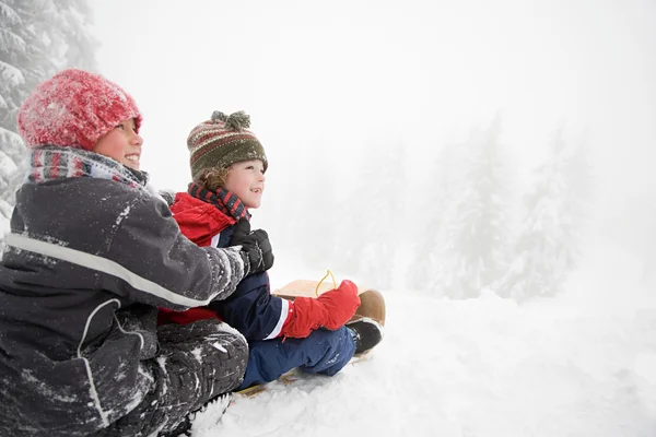 Jungen beim Rodeln im verschneiten Wald — Stockfoto