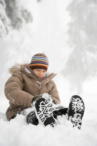 Jongen zitten in de sneeuw en plezier — Stockfoto