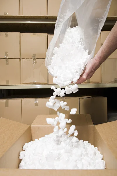 Person putting packing peanuts in box — Stock Photo, Image