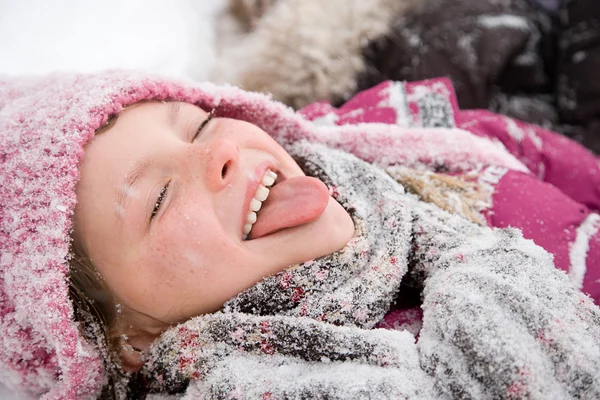 Девушка в снегу высовывает язык Стоковая Картинка