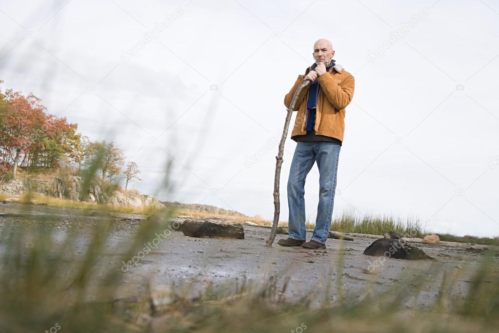 Mature man leaning on a stick
