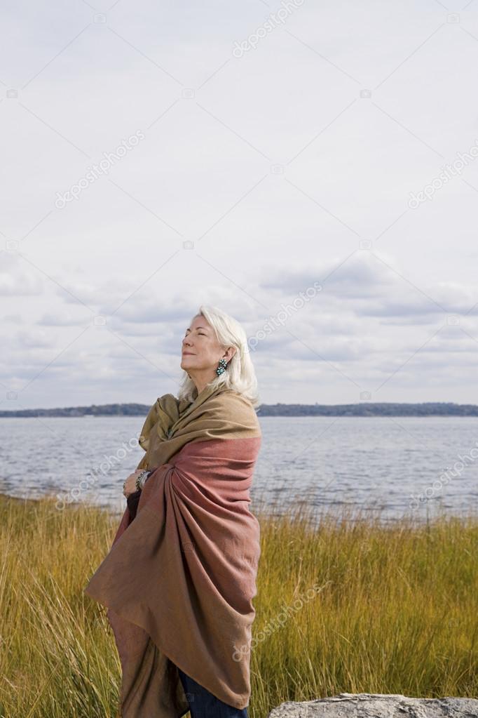 Senior woman standing near a lake