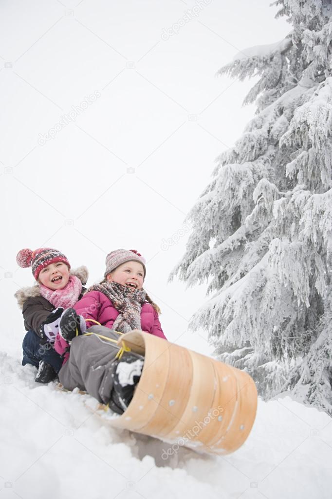 Girls on toboggan in the snowy forest