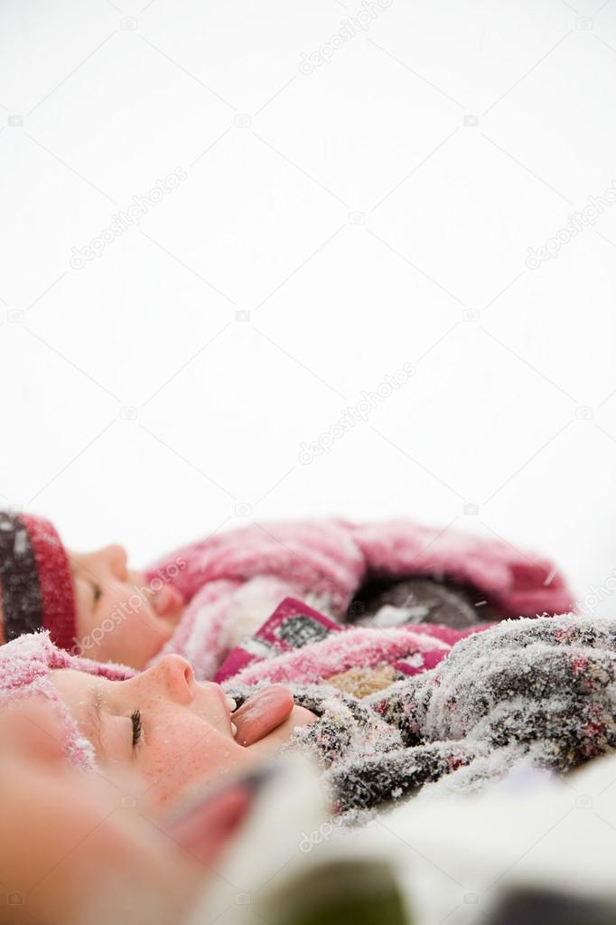 Children in snow sticking their tongues out