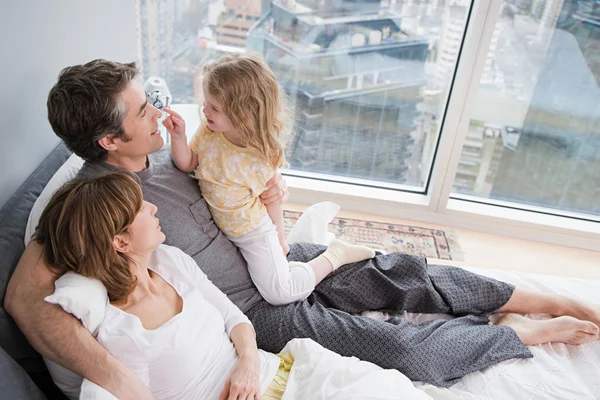 Familjen i sängen nära fönster — Stockfoto