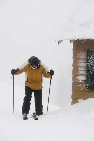 通过在雪地里的小木屋的滑雪者 — 图库照片