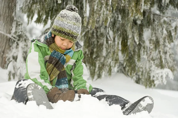 男孩坐在雪地上 — 图库照片