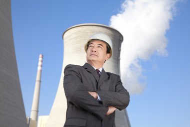 Businessman in front of cooling tower clipart
