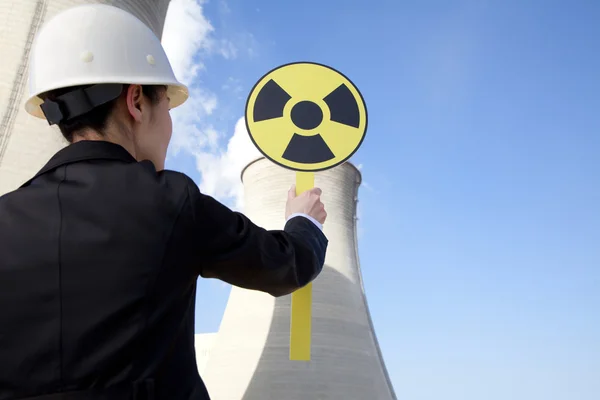 Engineer in front of cooling towers with sign — Stock Photo, Image