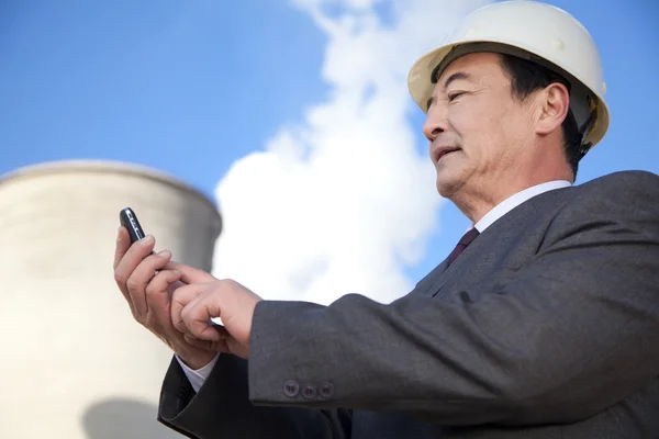 Businessman texting at power plant — Stock Photo, Image