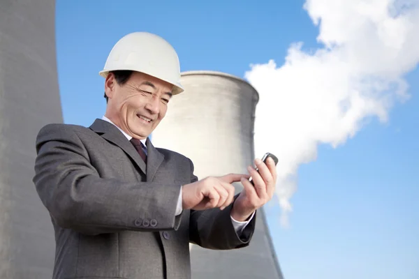 Businessman texting at power plant — Stock Photo, Image