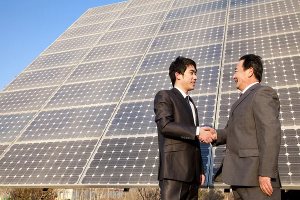 Shaking hands in front of solar panels Stock Picture