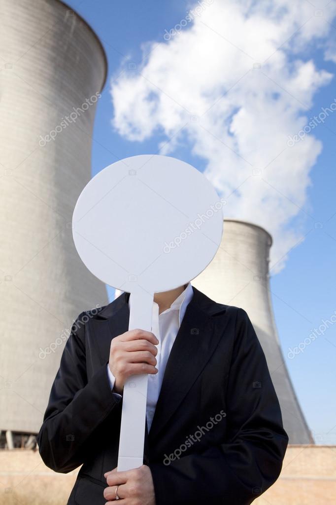 Engineer in front of cooling towers with sign