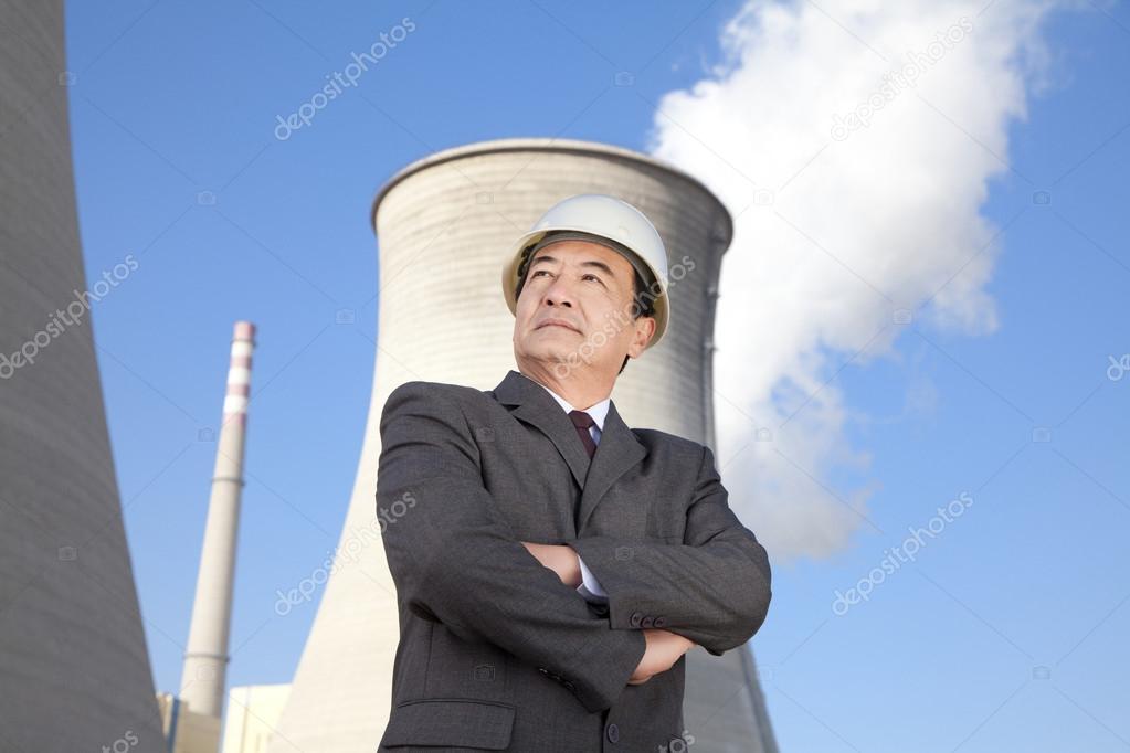 Businessman in front of cooling tower