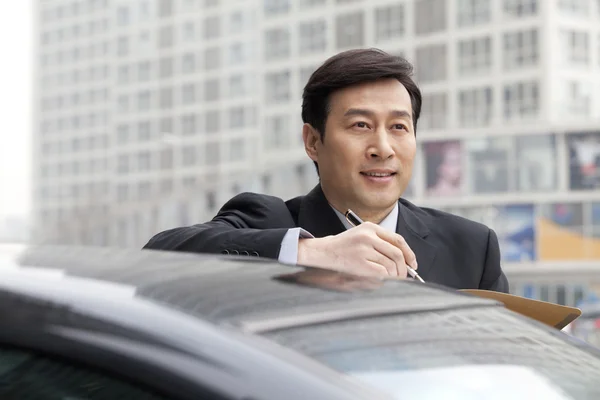 Businessman working outdoors on car — Stock Photo, Image