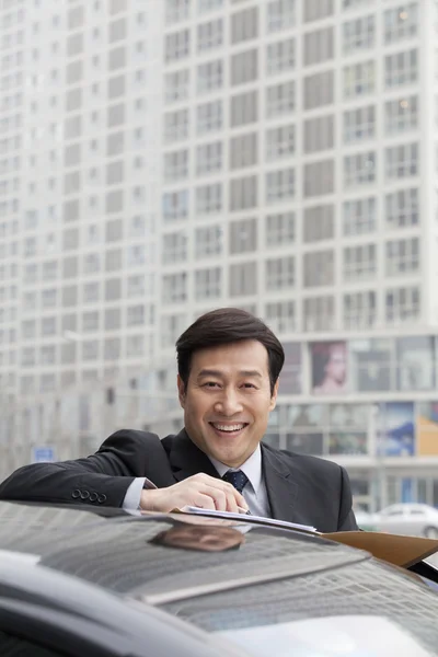 Businessman working outdoors on car — Stock Photo, Image