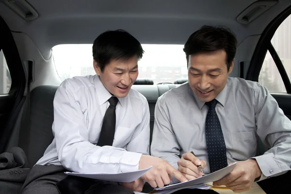 Businessmen working in back of car — Stock Photo, Image