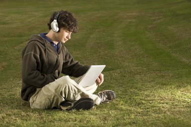 Erkek öğrenci açık havada bir dizüstü bilgisayar kullanarak