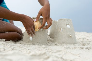Anne ve çocuk bir kabuk bir sandcastle koyarak