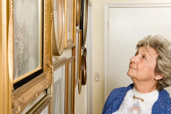 Женщина смотрит на стену с фотографиями — стоковое фото