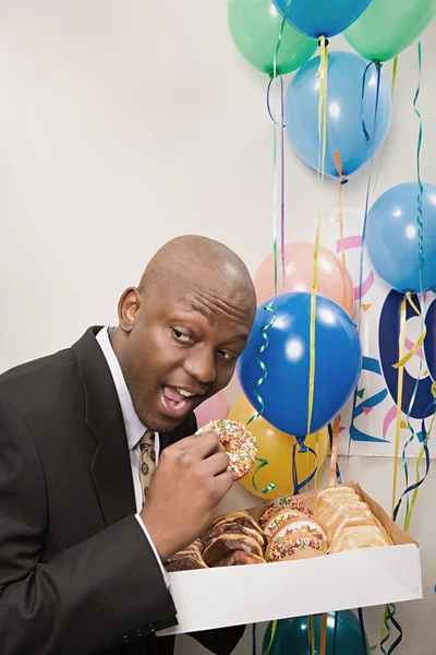 Businessman secretly eating doughnuts — Stock Photo, Image