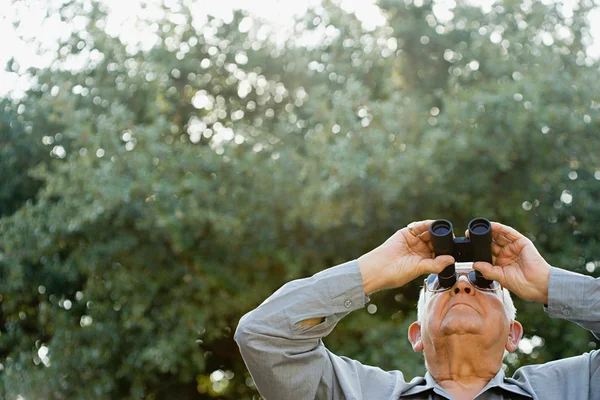 Старший человек смотрит сквозь бинокль — стоковое фото