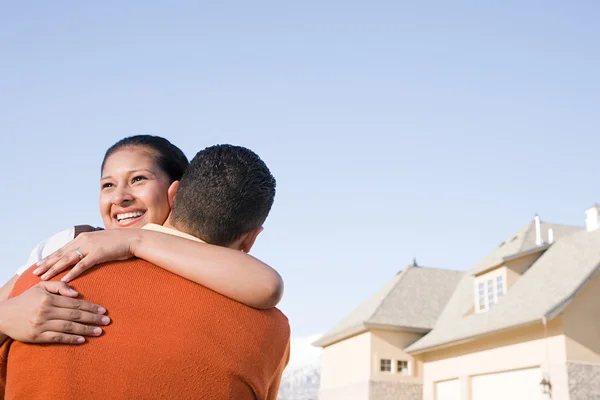 Un couple étreignant devant leur nouvelle maison — Photo