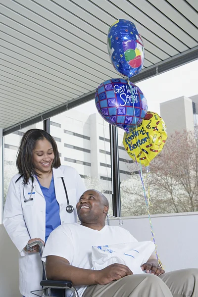 Arzt schubst Patientin im Rollstuhl — Stockfoto