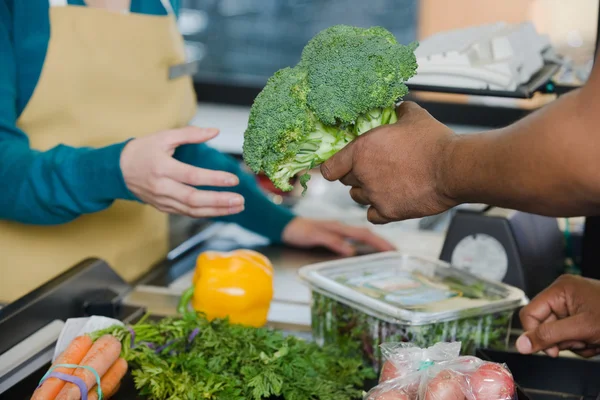 Un client remet un brocoli à un assistant de vente — Photo